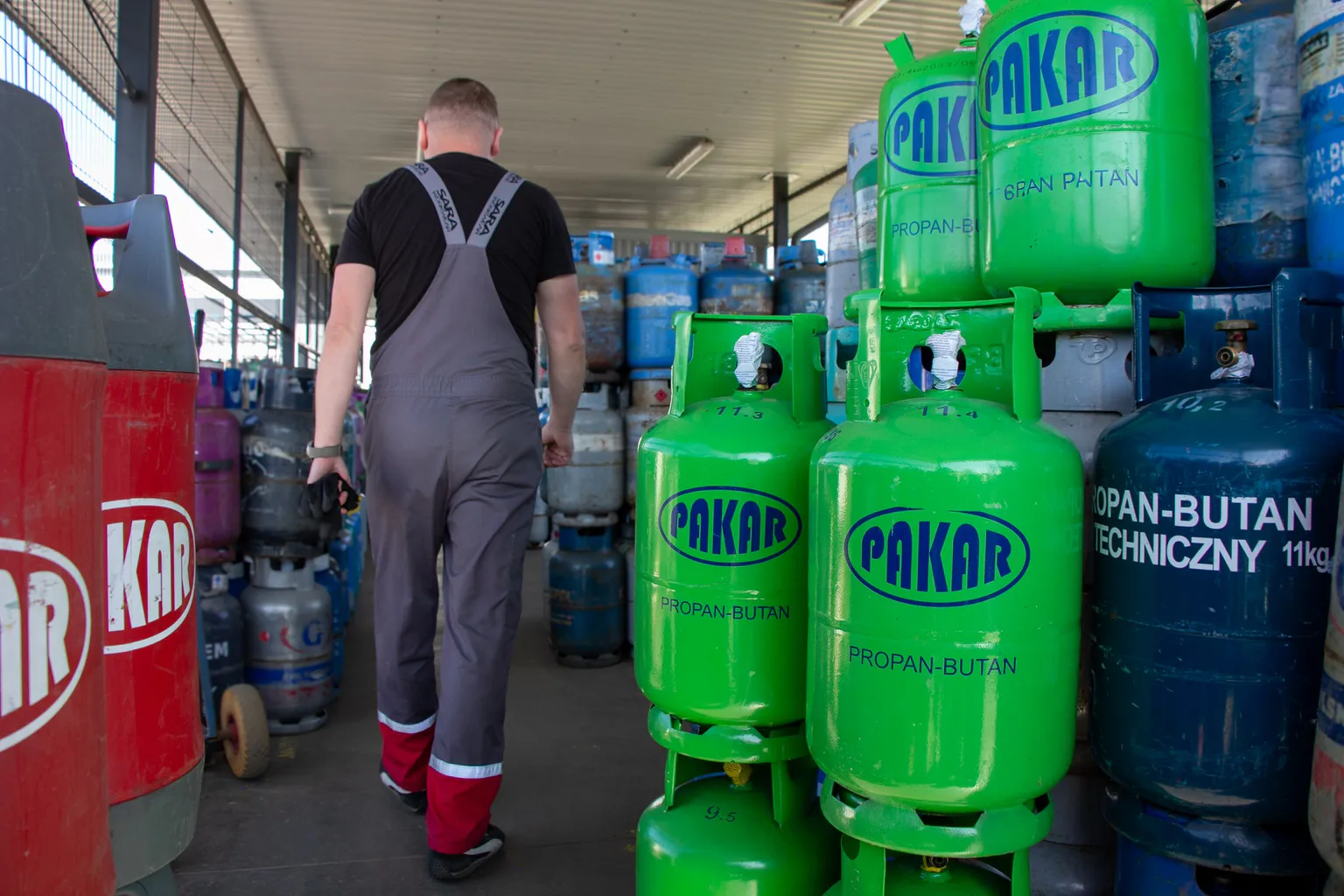 Pracownik idzie alejką zadaszonego magazynu butli gazowych PAKAR, między stosami butli